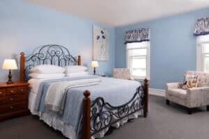 First bedroom in Penn with a queen size bed. A large flower print hangs to the side of the bed.